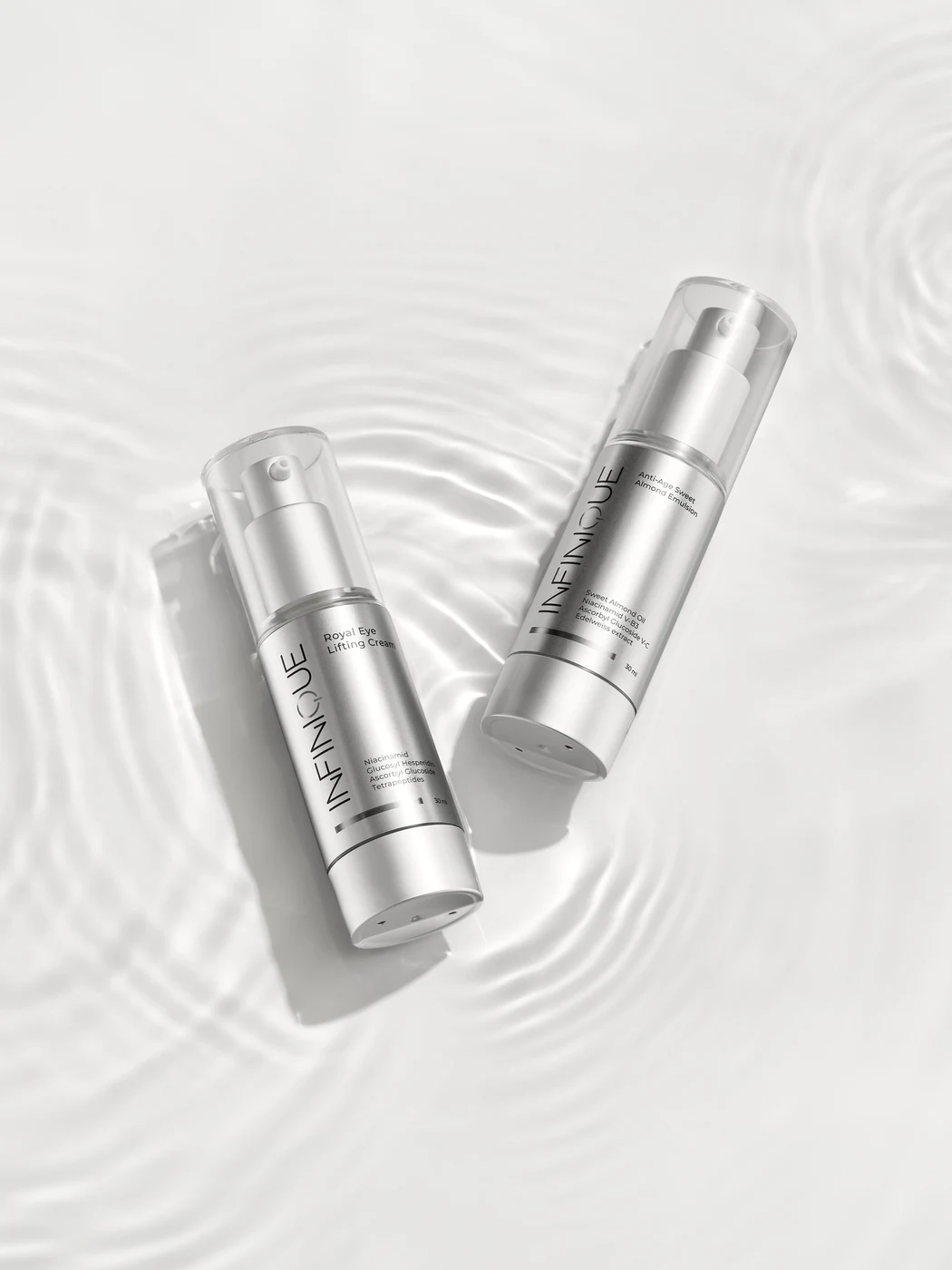 INFINIQUE Royal Eye Lifting Cream and Sweet Almond Emulsion in silver bottles on water ripples